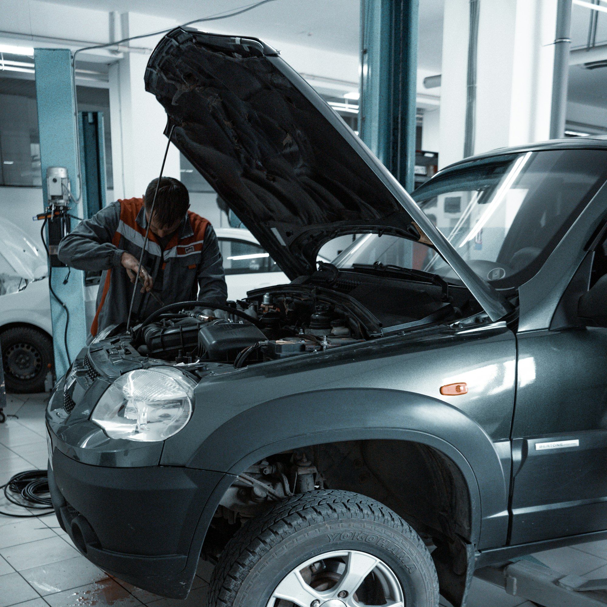 A car on a lift in a workshop with the bonnet open
