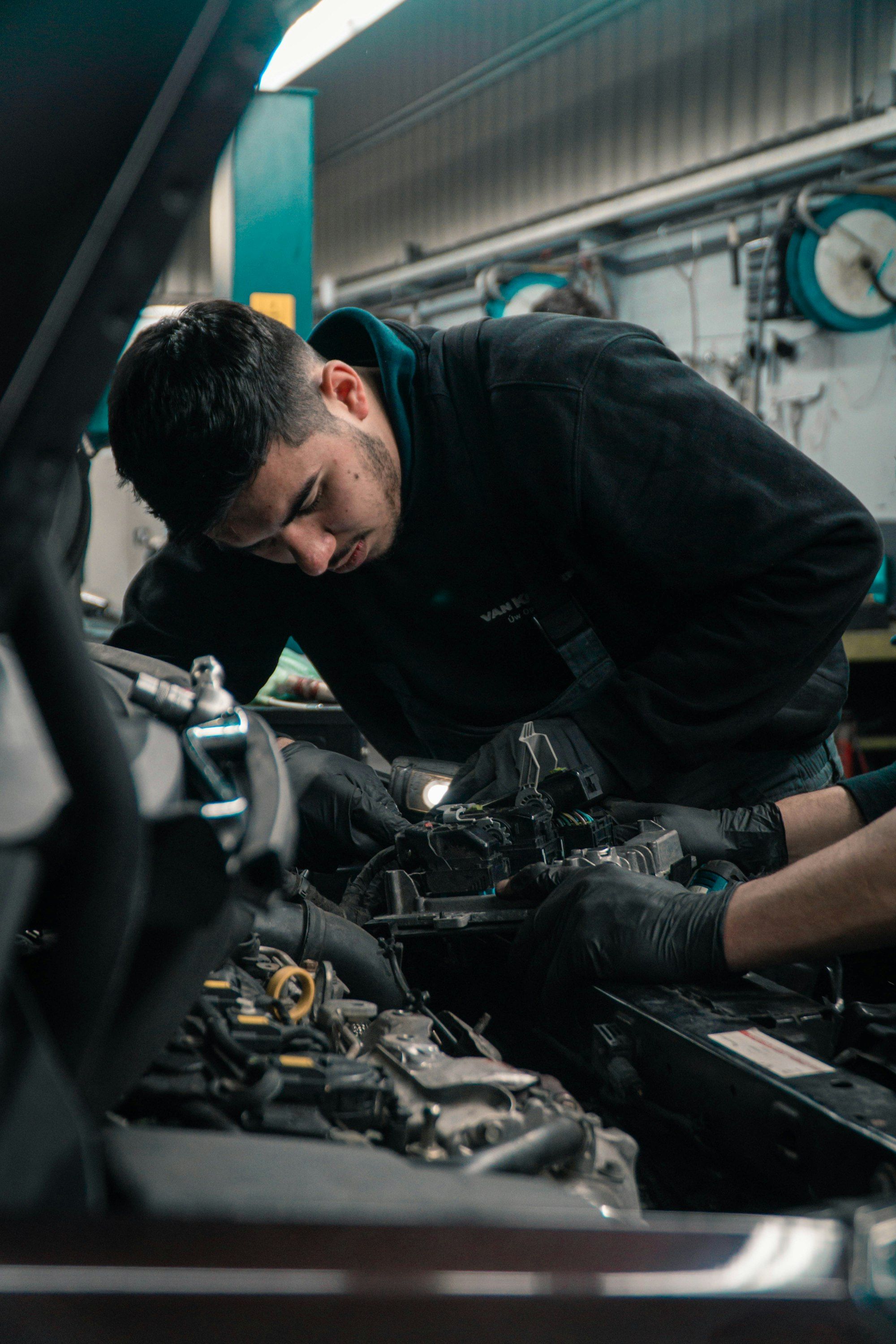A technician working in the engine bay of a car in a workshop