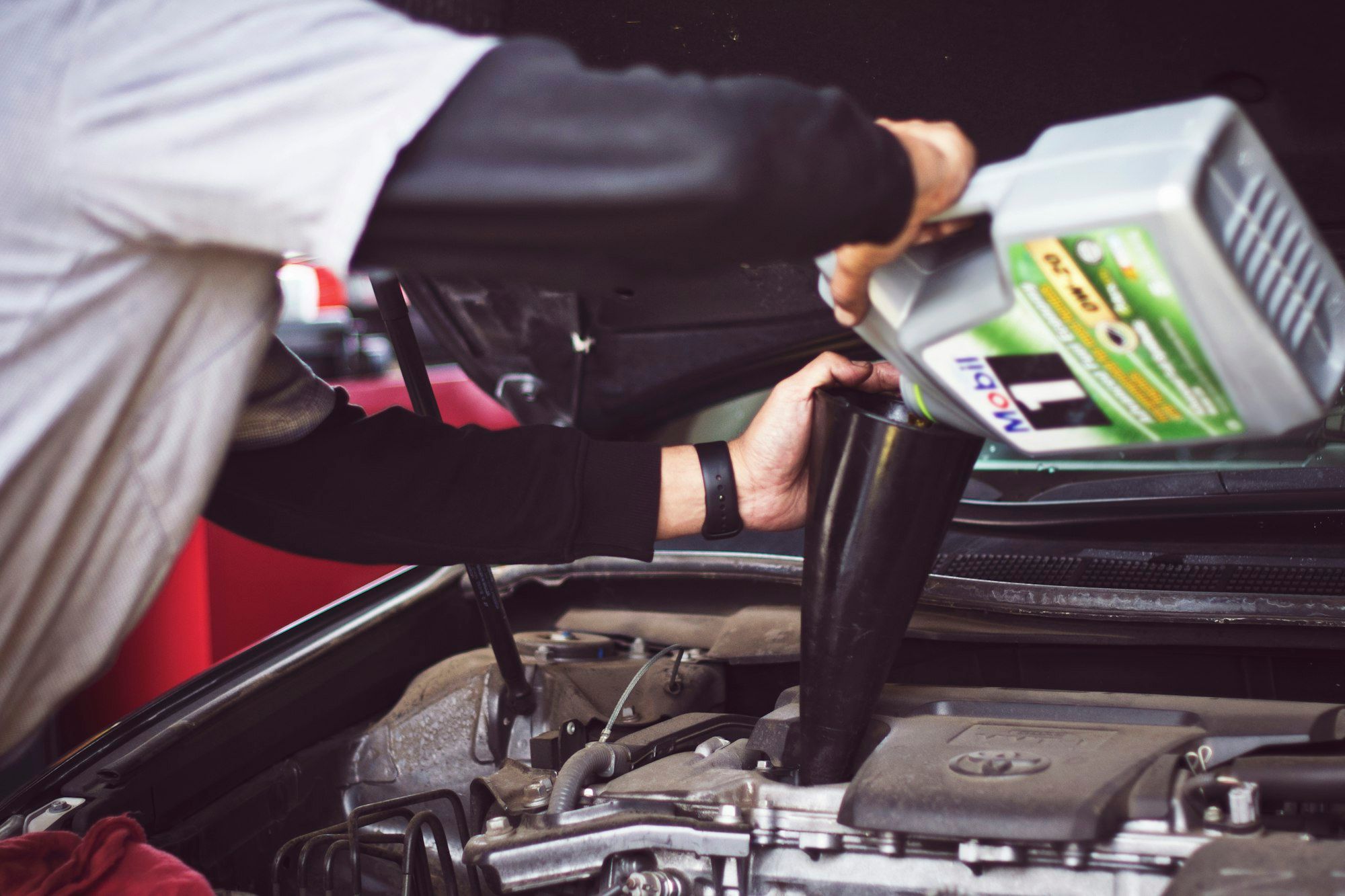 Fresh engine oil being poured into a car engine