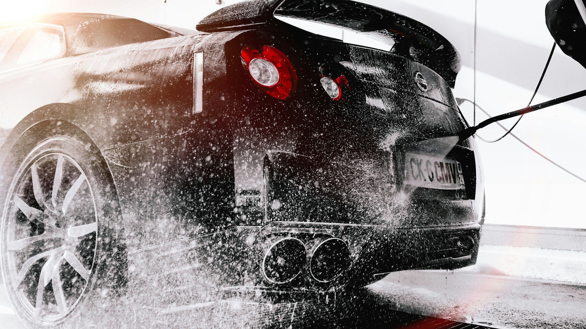 A sports car being sprayed with a pressure washer