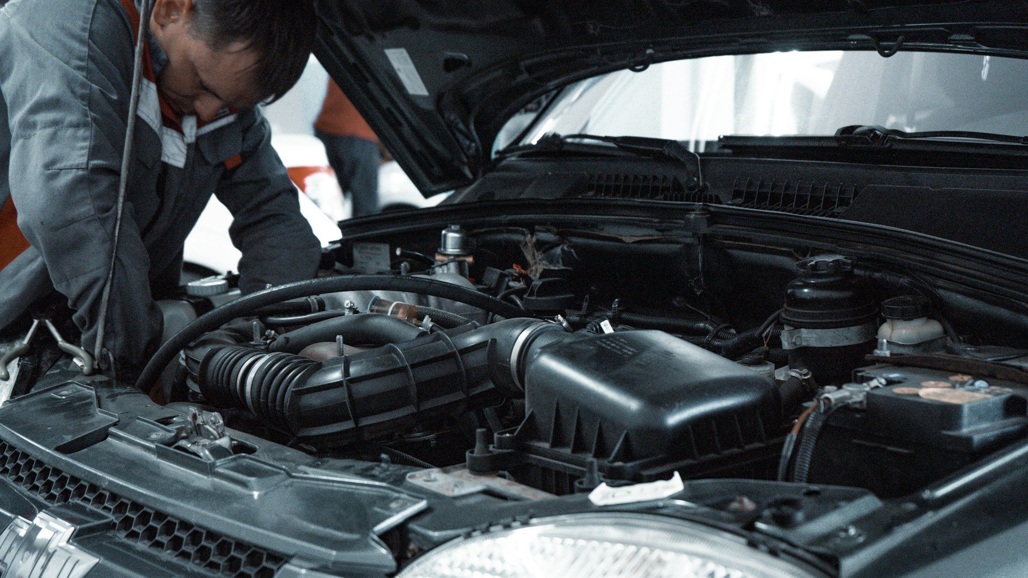 Mechanic checking components in an open engine bay