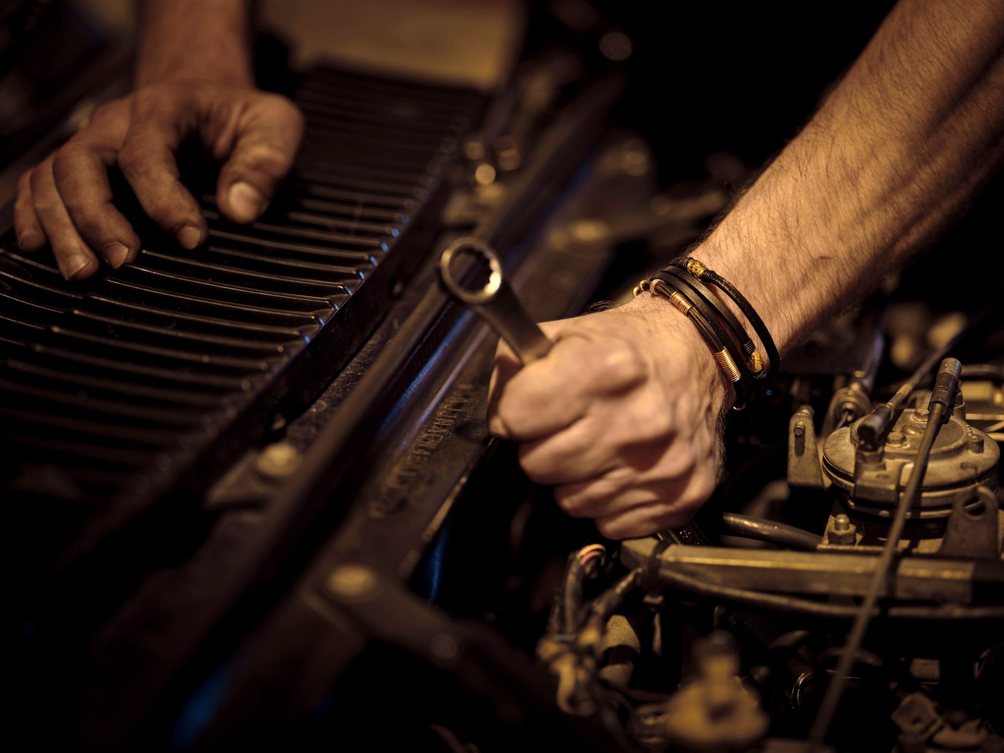 Hands turning a wrench on an engine
